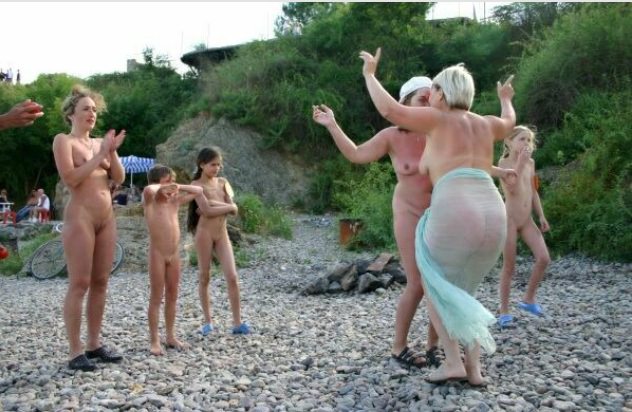 The company of nudists dances on a beach [WorldNudism]